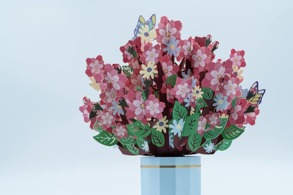 Vibrant paper flower bouquet with butterflies in a vase, perfect for a cheerful decor.