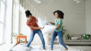 Two young women having a pillow fight indoors.