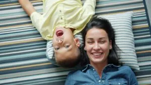 Mother and son lying on striped rug smiling